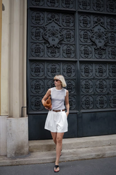a lady wears a striped tank top with A-line white shorts